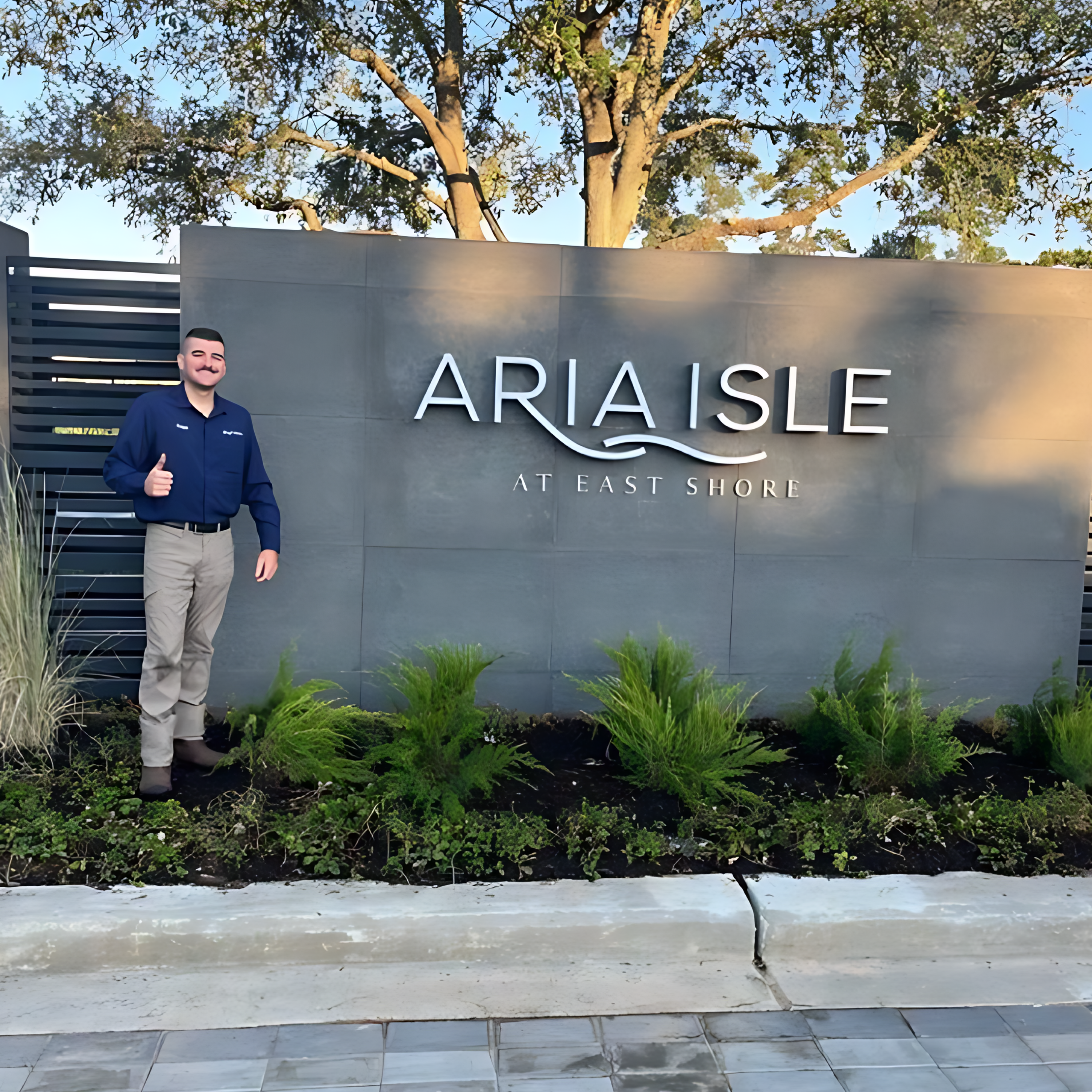 A man standing in front of a sign for an apartment complex.
